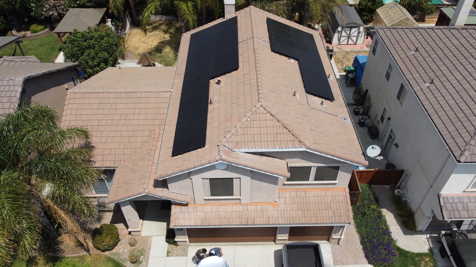 Aerial view of a two-story Southern California home with black solar panels on a tile roof