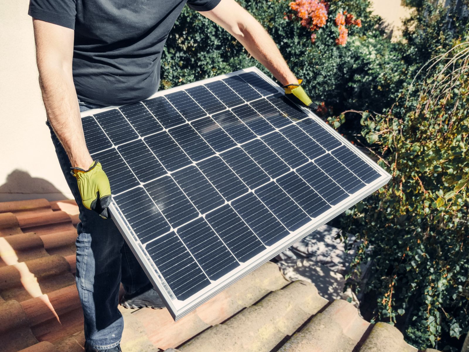 VertX installer carrying a solar panel across a tile roof